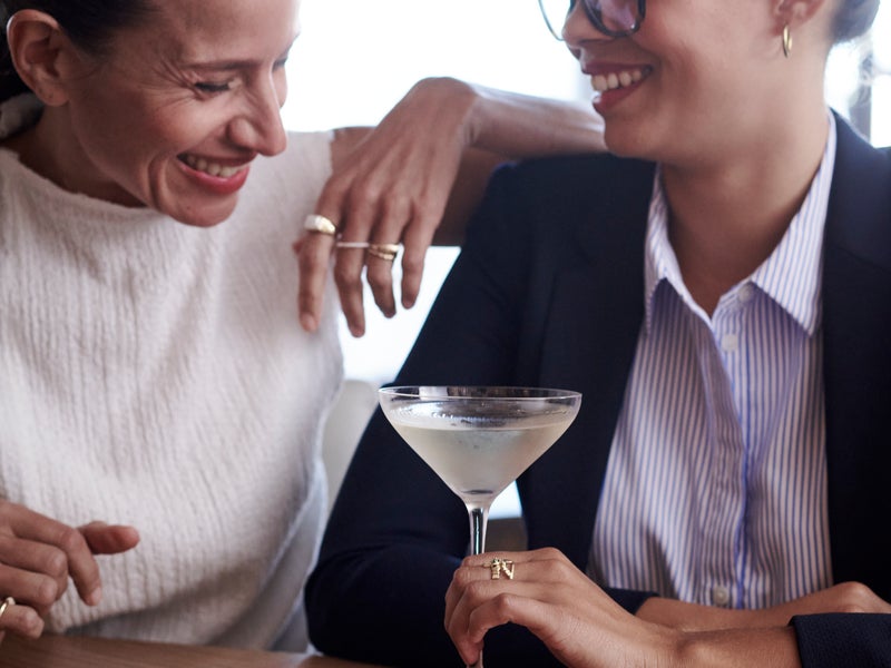 People laughing, with a cocktail