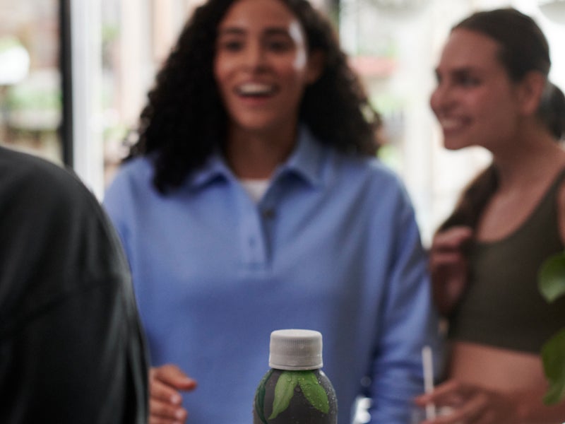 Person holding a bottle of sparkling water talking to another person