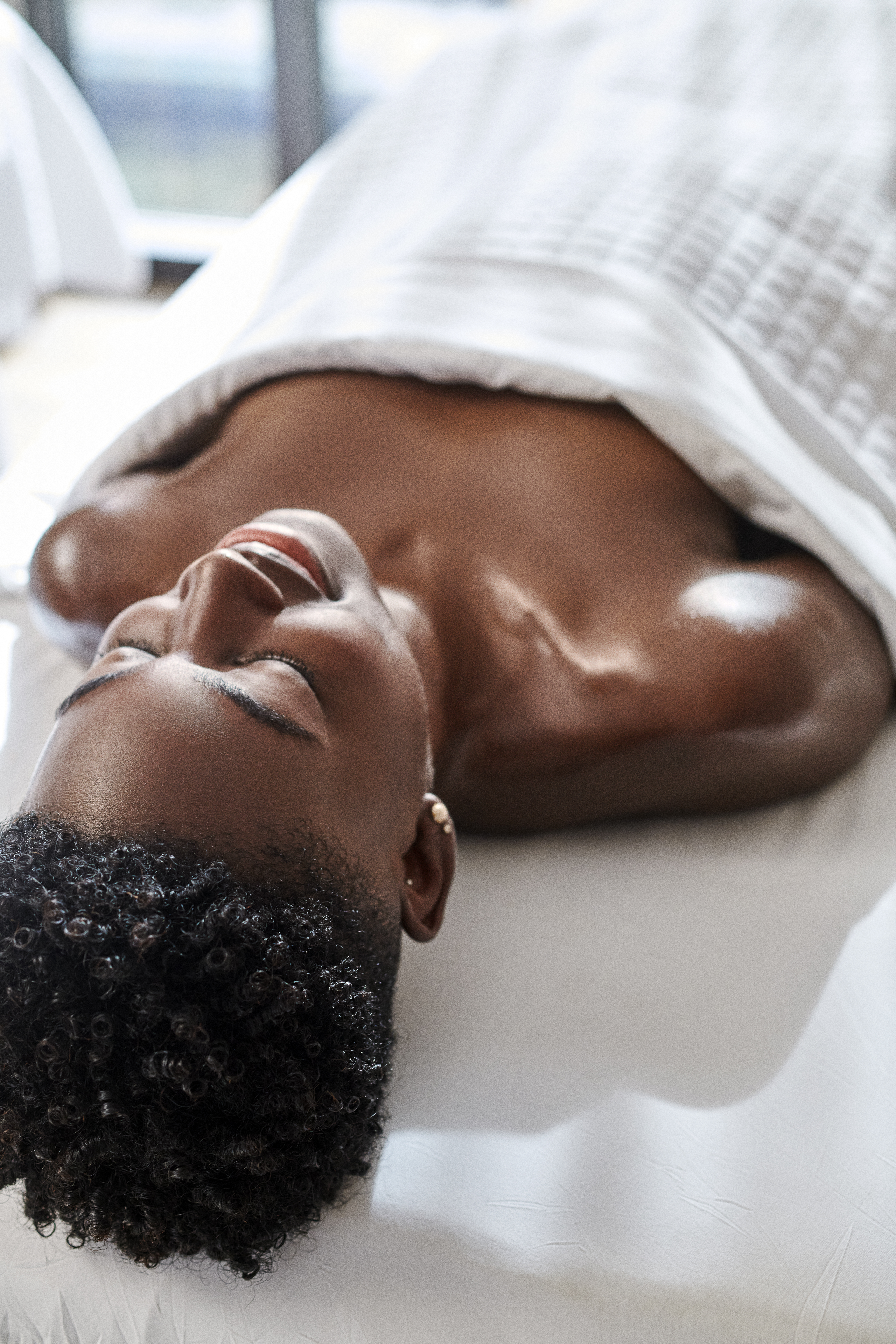 Una donna sdraiata a faccia in su su un lettino da massaggio, con gli occhi chiusi, che si rilassa