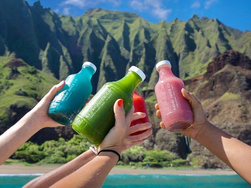 People holding bottles of Kauai juice