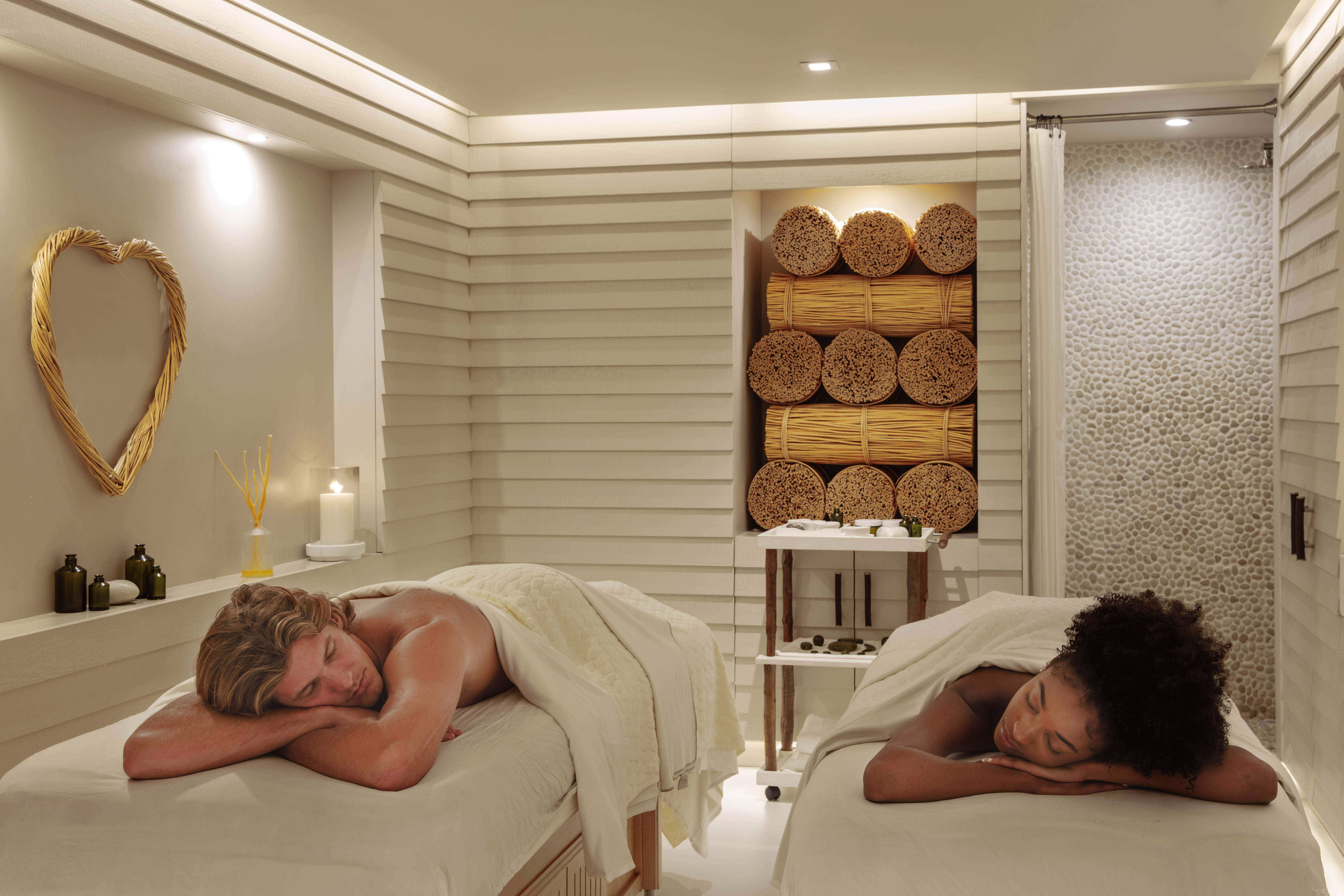 A couple, one man and one woman, lay face down on massage beds, relaxed