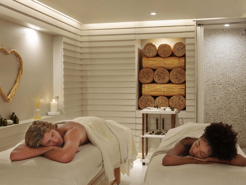 A couple, one man and one woman, lay face down on massage beds, relaxed