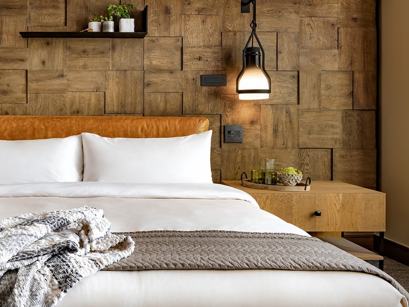 A made bed with white sheets surrounded by modern yet rustic décor