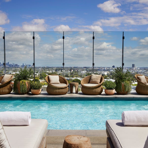 A view of the rooftop pool from between two poolside lounge chairs