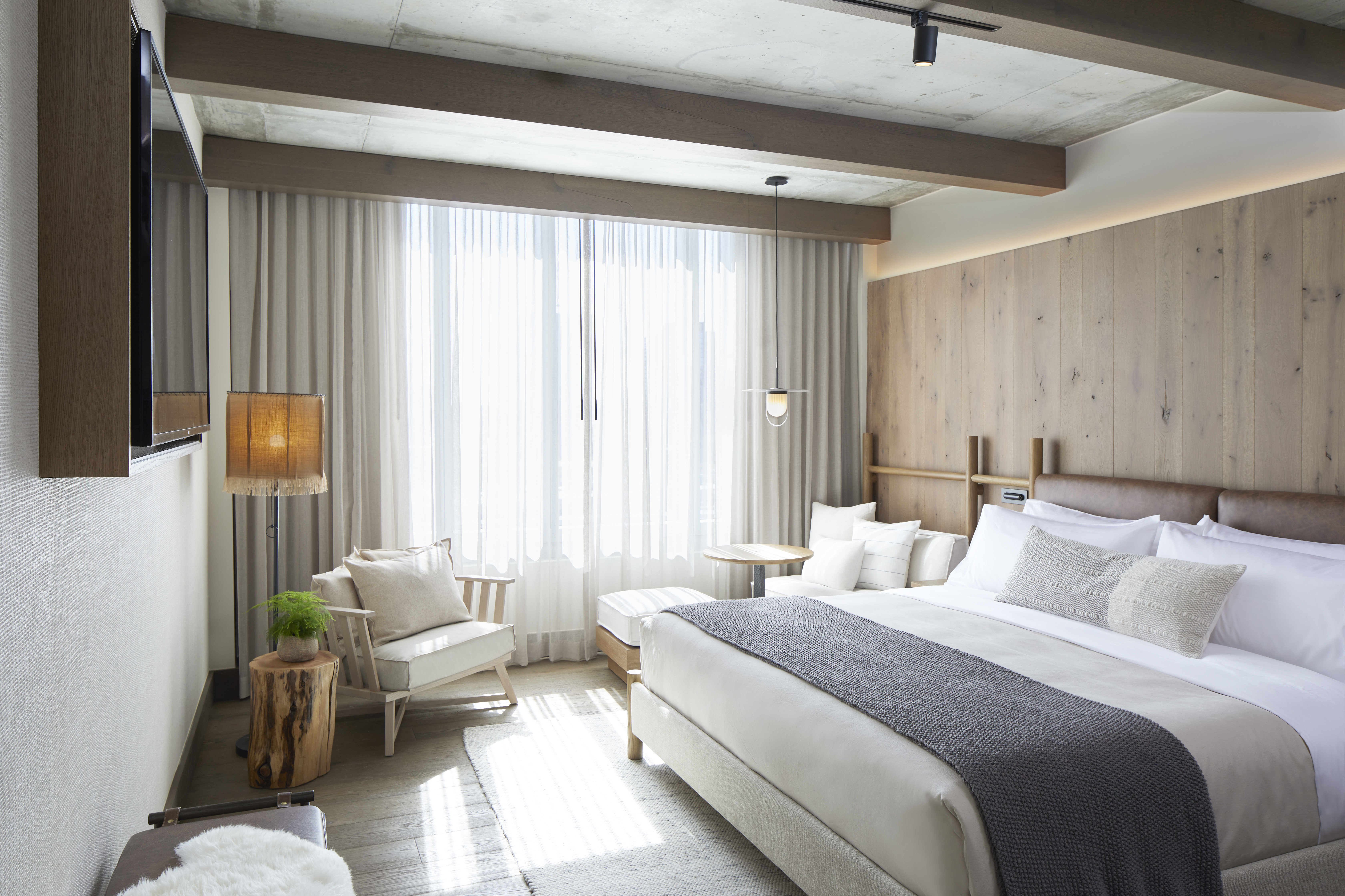 A large king sized bed bathed in sun from the nearby window