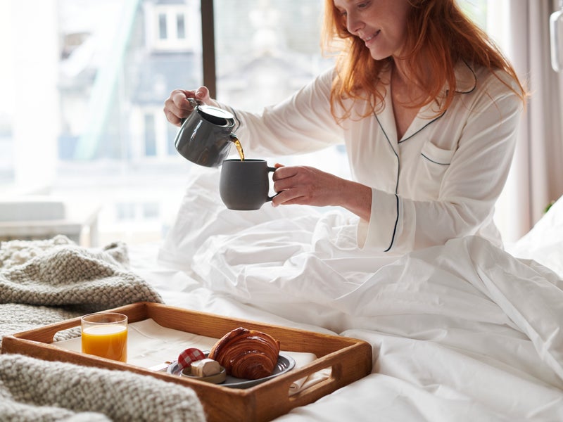 A woman in bed pouring coffee
