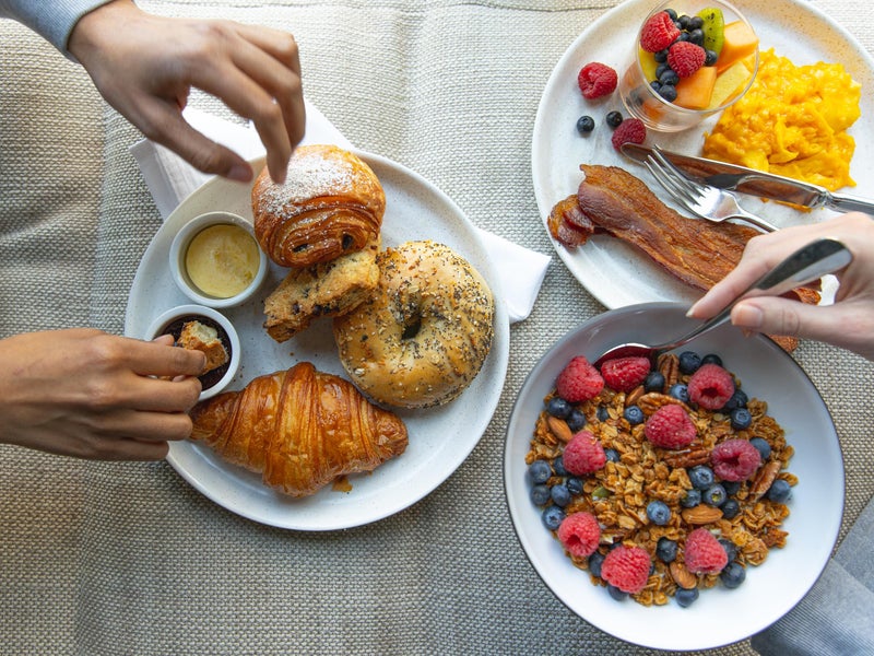 Plates with bagels, croissants, and a bowl of cereal