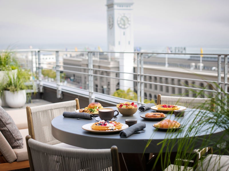 Breakfast served on a table set for three on the Terrace patio.  The San Francisco ferry building clock tower can be seen nearby.