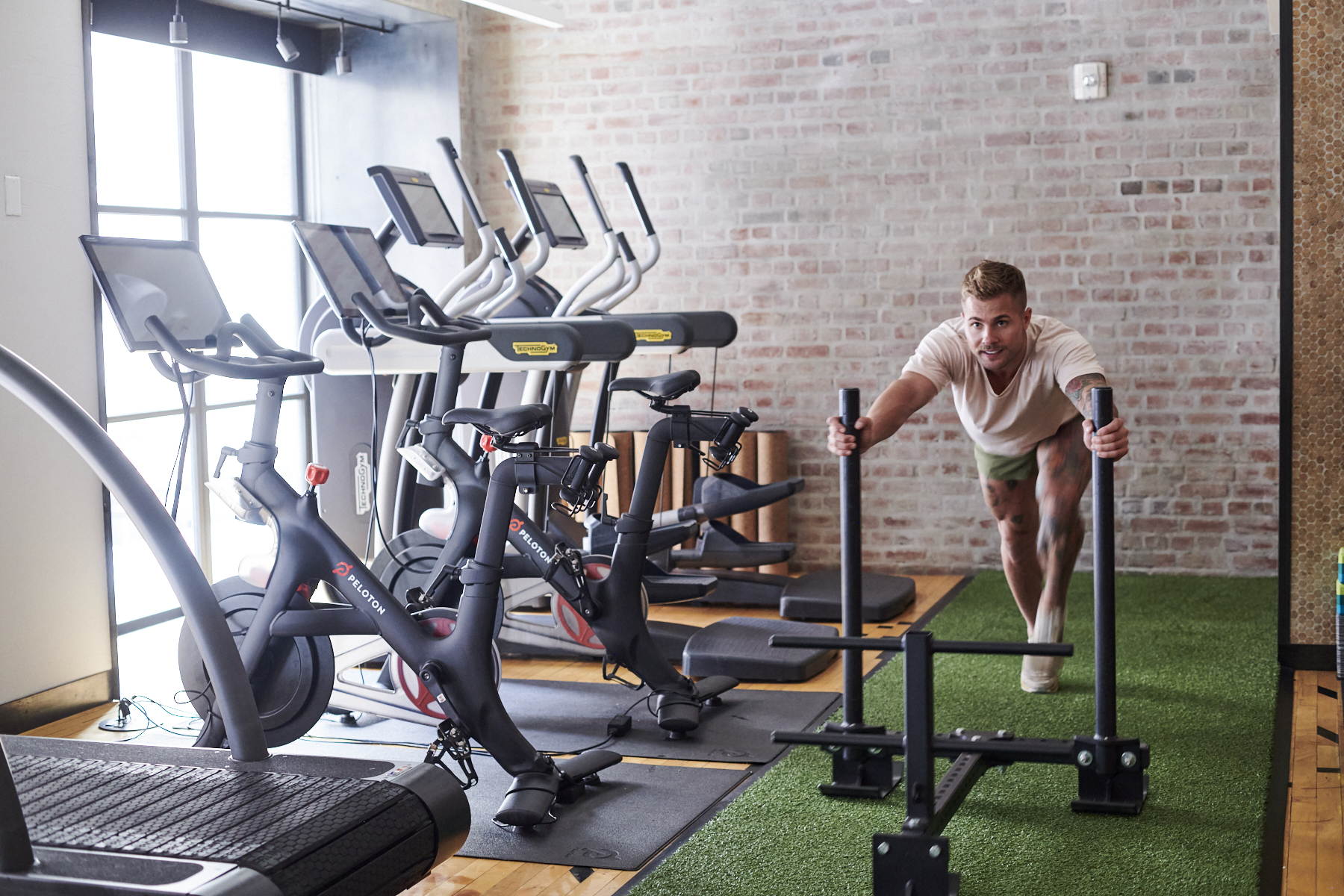 Gym with treadmills and man pushing weights on turf