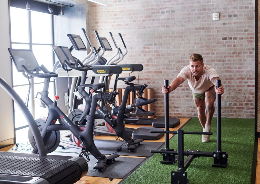 Gym with treadmills and man pushing weights on turf