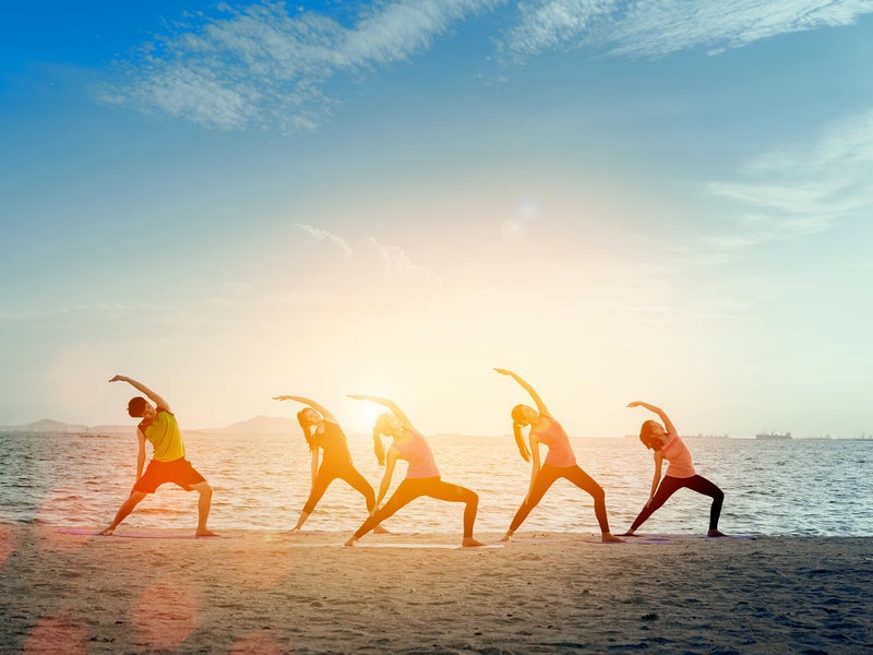 A group of people doing yoga on a beach