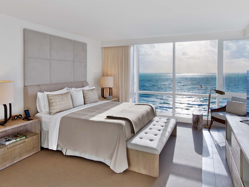 A bedroom with a window out to the ocean