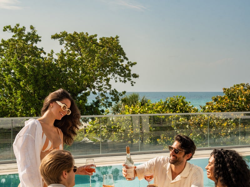 People drinking wine at the pool.