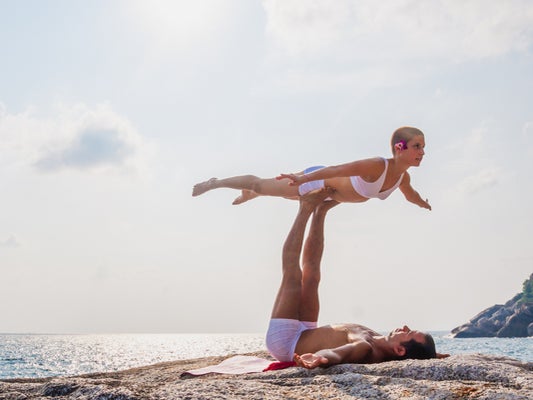 Two people doing acrobatic yoga on the beach