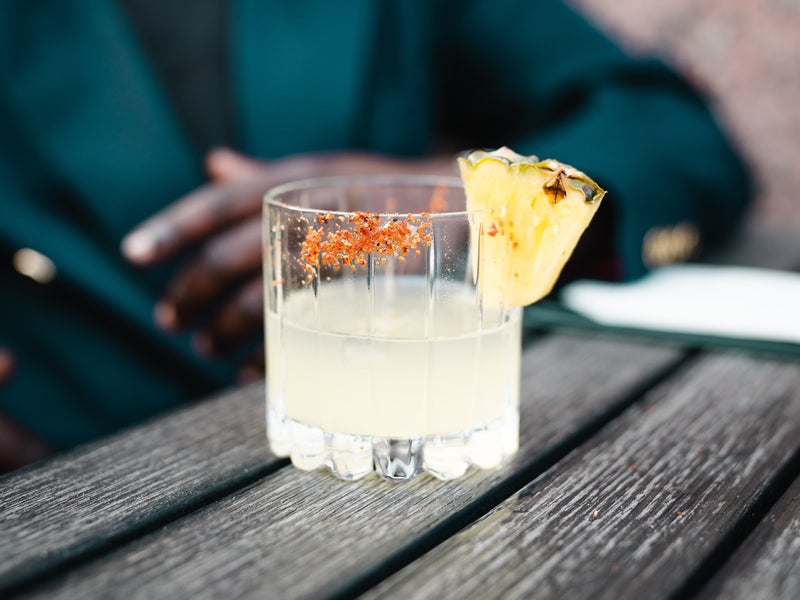 A half empty cocktail with a pineapple wedge and salt rim