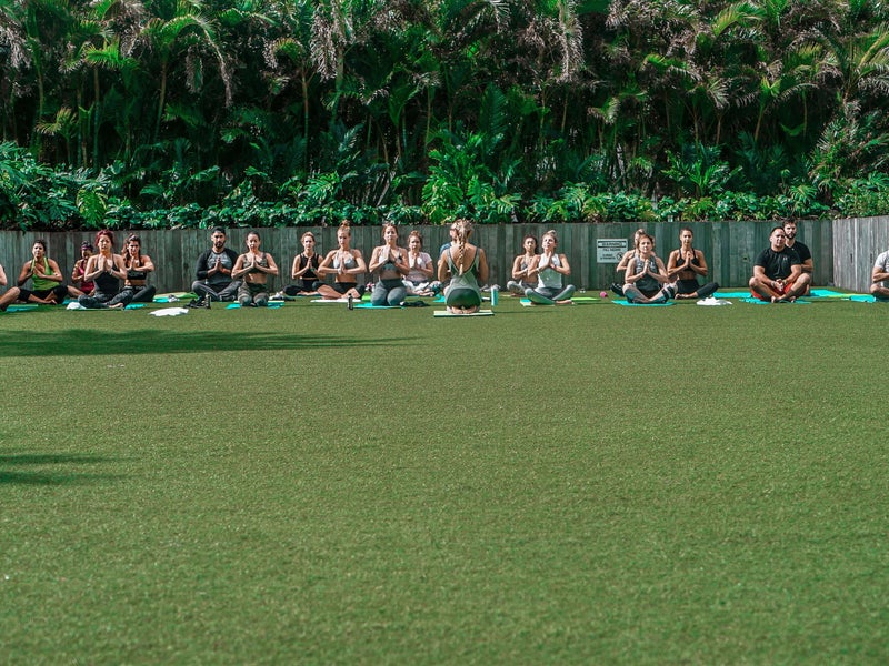 Class of people doing yoga outdoors in a field