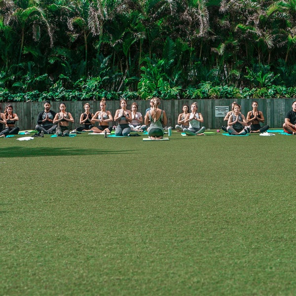 Class of people doing yoga outdoors in a field