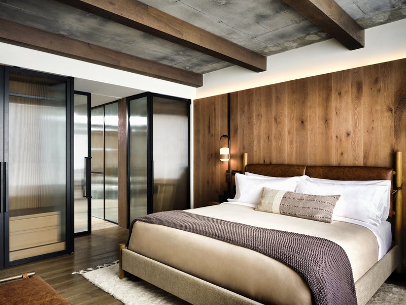 A large king sized bed with a wood panel wall behind it