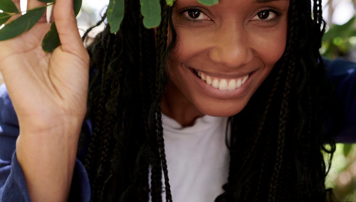 Person smiling behind a tree branch