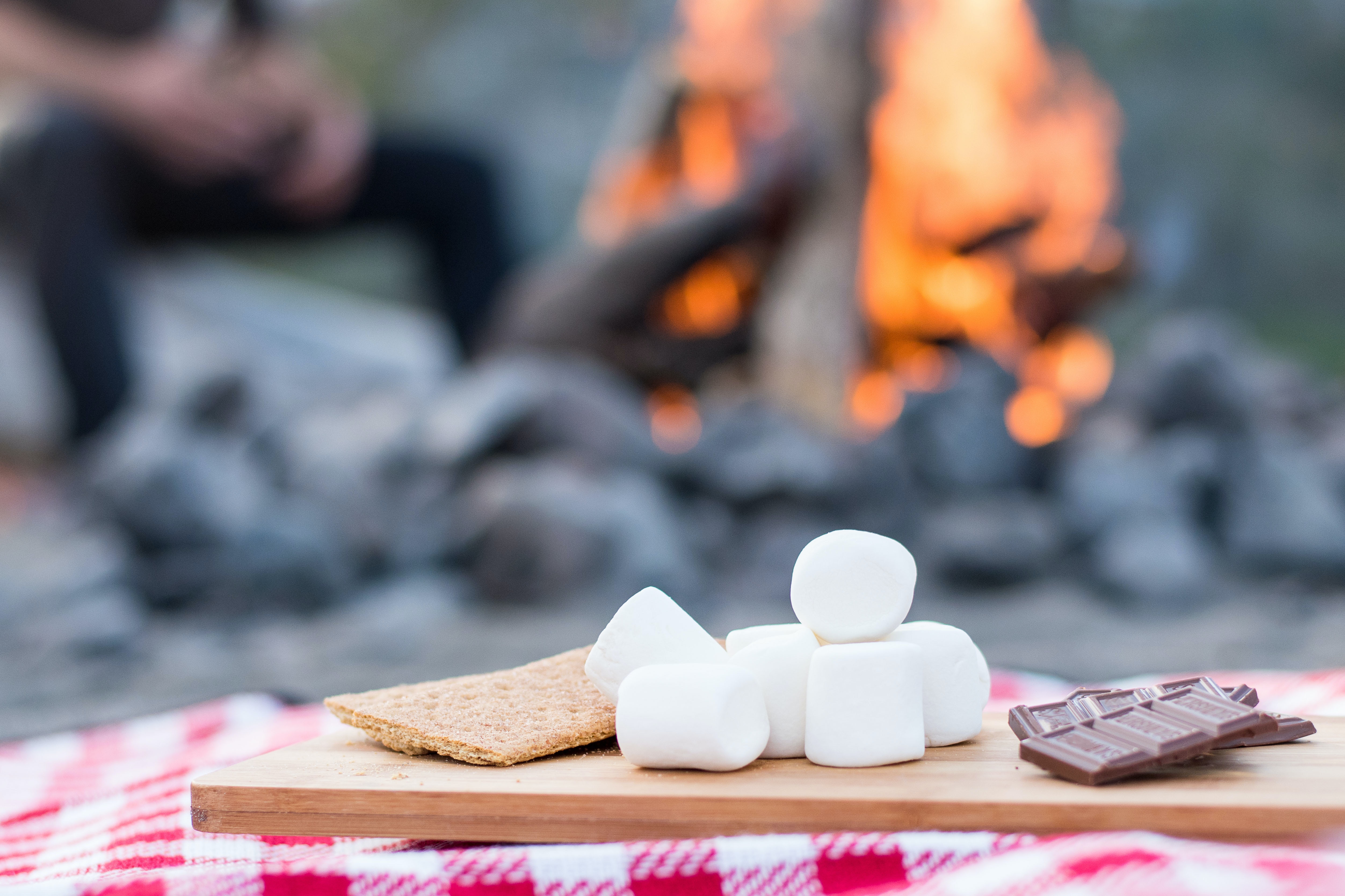 Smores ingredients on a tray with a campfire in the background