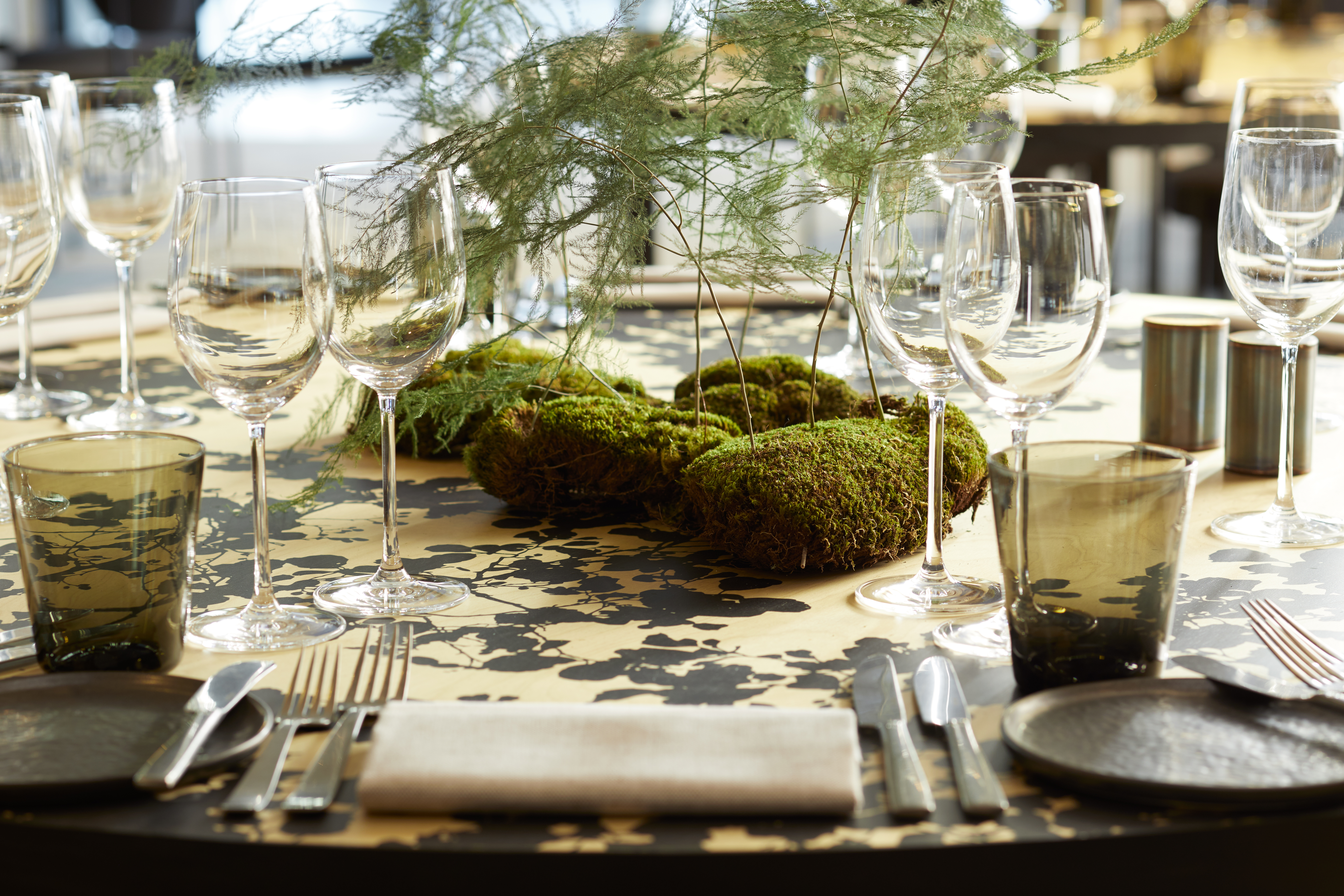 Trees stemming from moss sit center table creating a unique and elegant center piece.  Elegant glassware is set for each table placement.