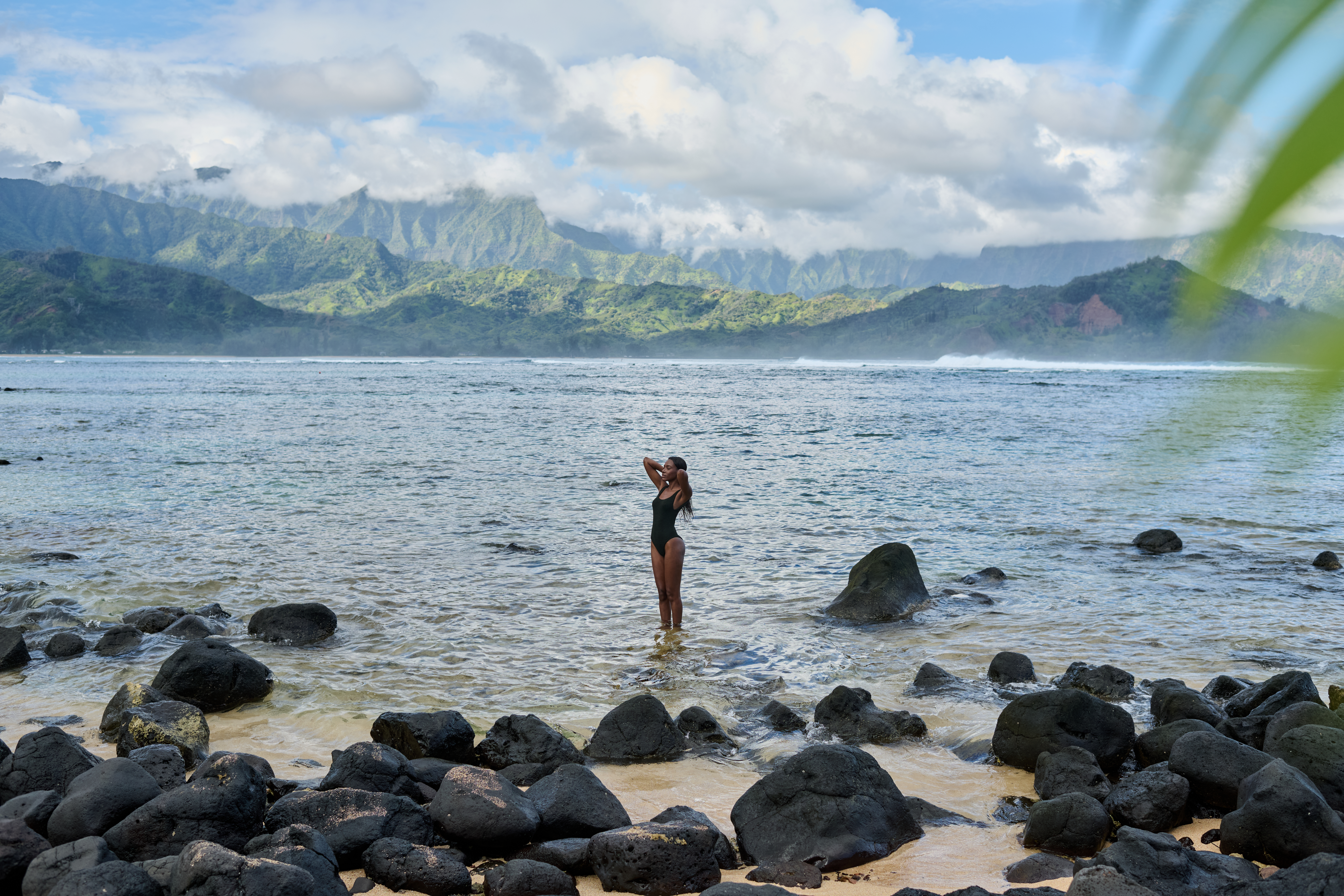 woman standing in ocean with mountains in background