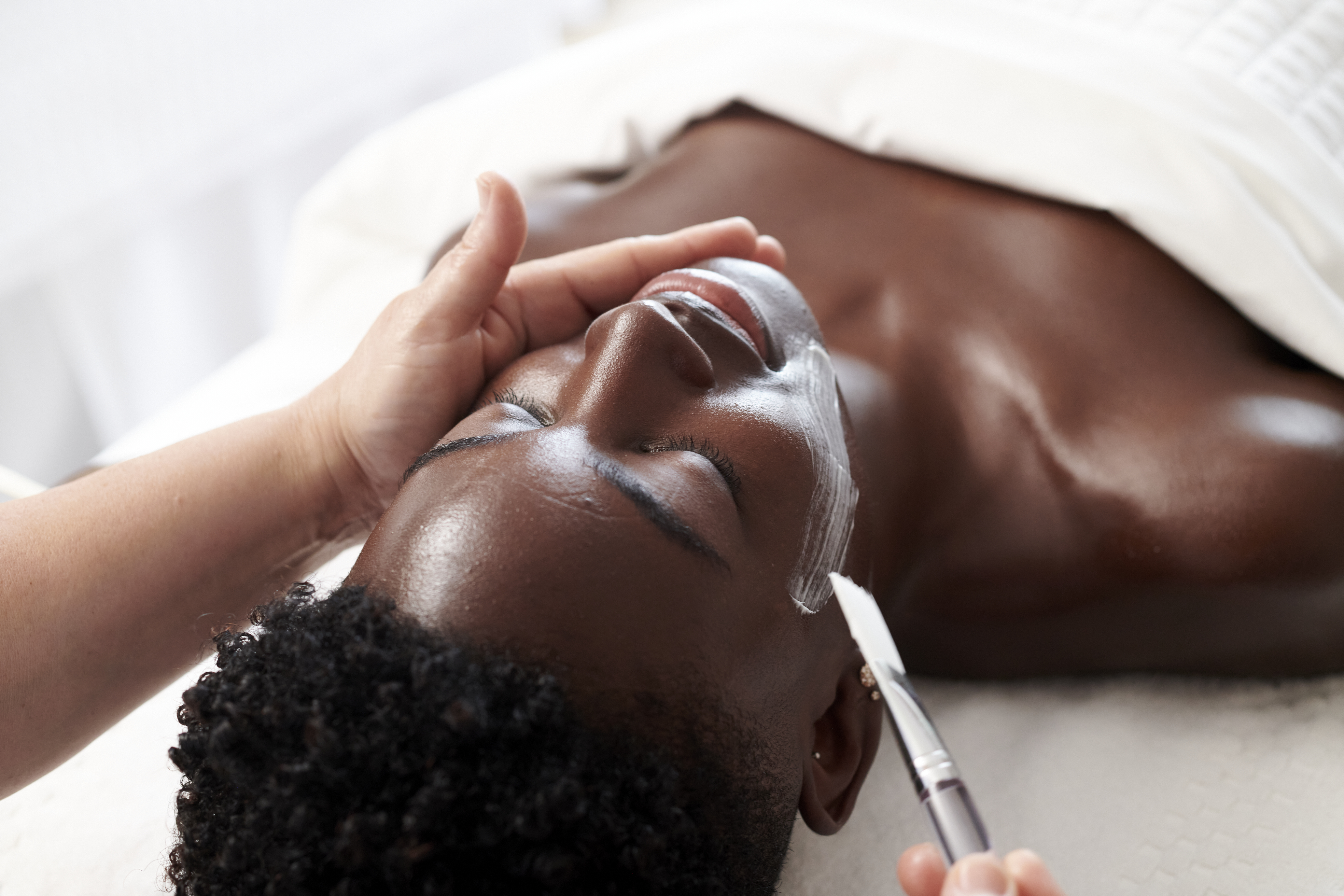 A woman at the spa getting a facial mask