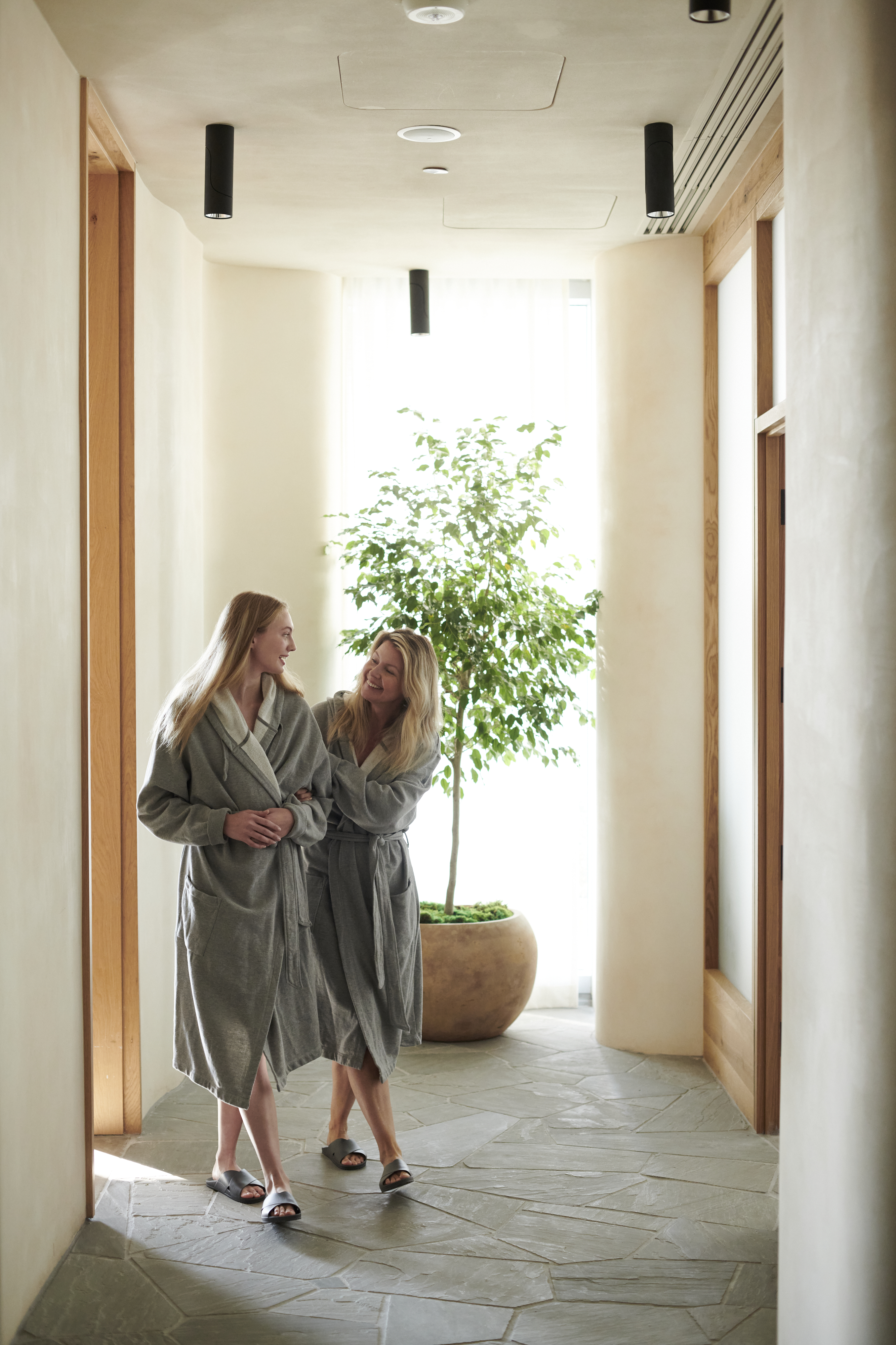 Two people wearing robes walking down a hallway