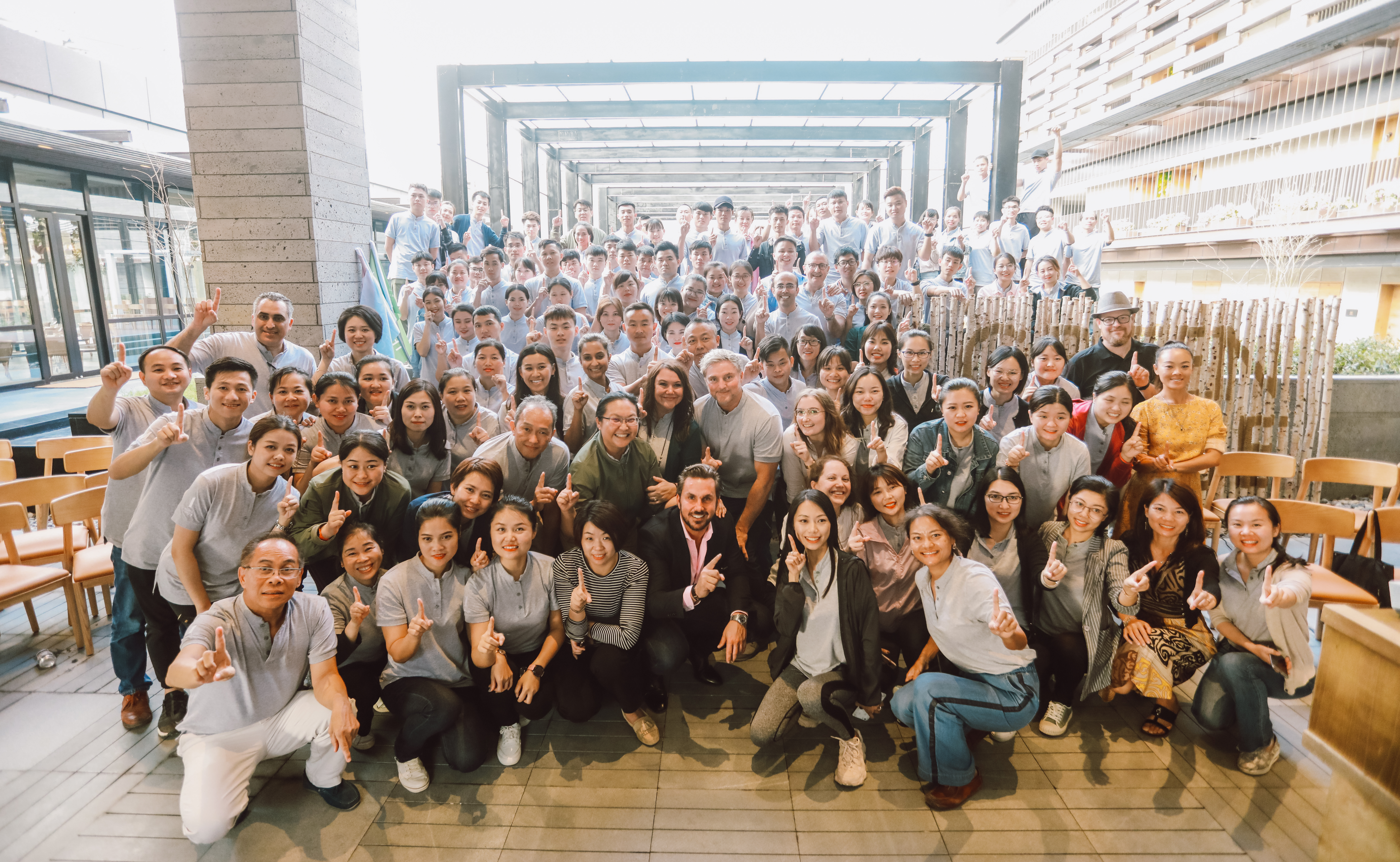Gruppo di persone riunite per una foto con il dito indice alzato