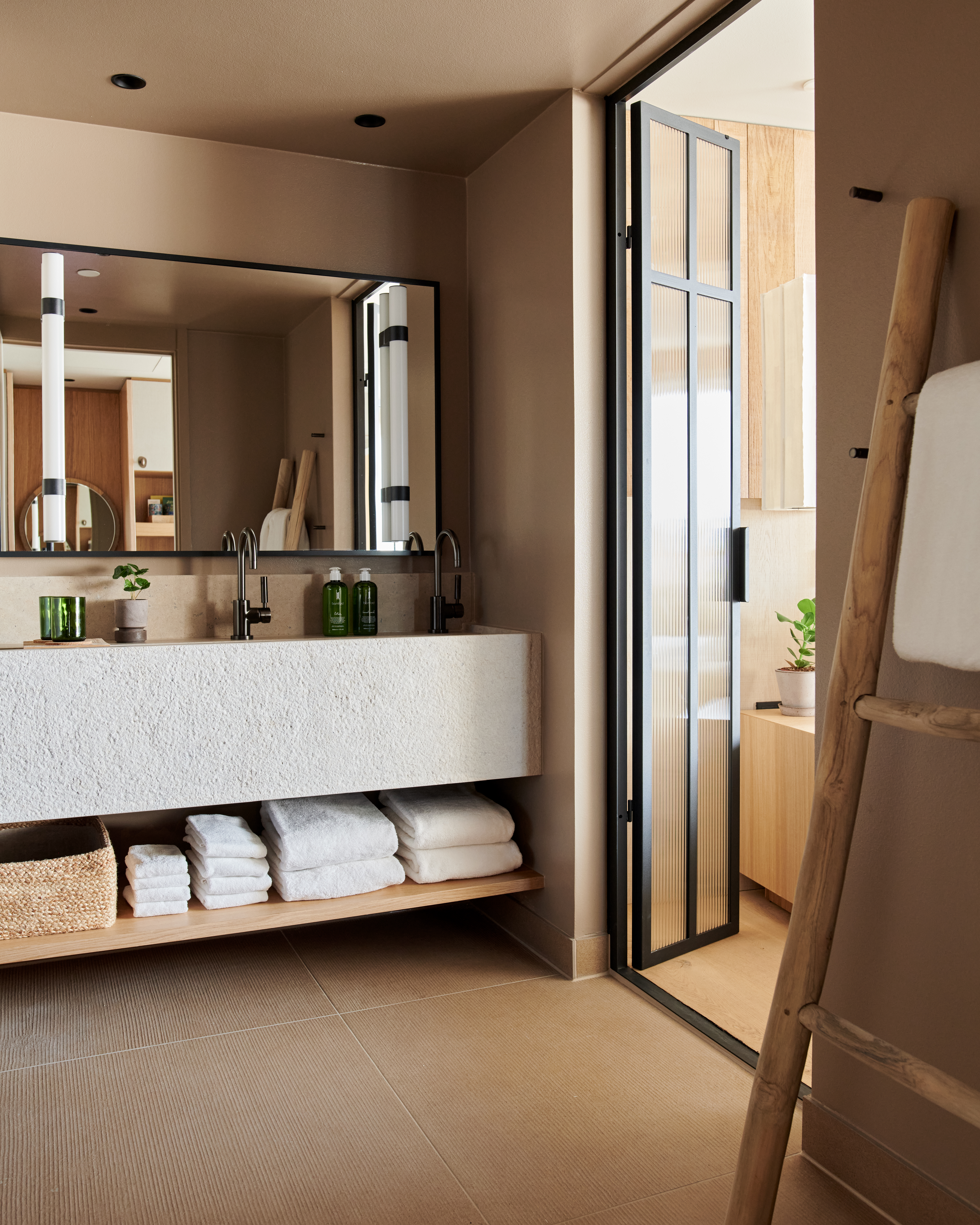 Een grote badkamerspiegel in een kamer vol handdoeken