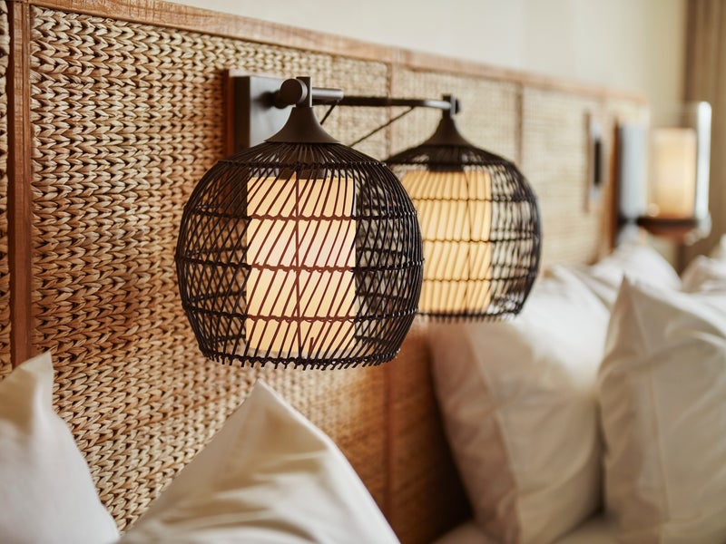 Lamps hanging on the wall at the head of a bedframe
