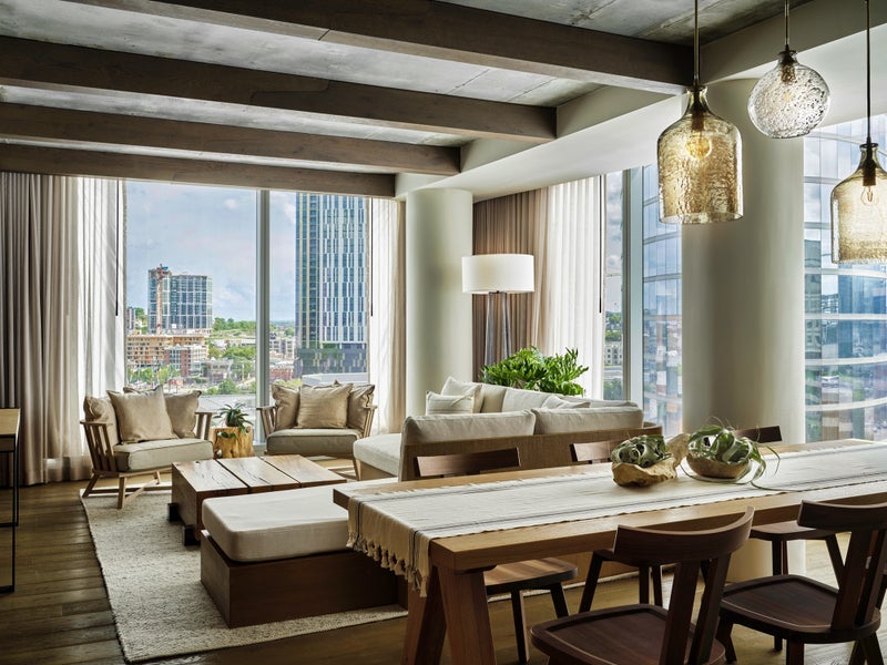 1 Hotels Nashville penthouse suite with a dining room table and living room furniture overlooking views of the city