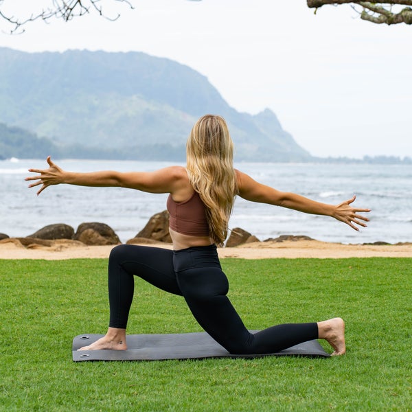 Woman doing yoga position with ocean and hills in the background