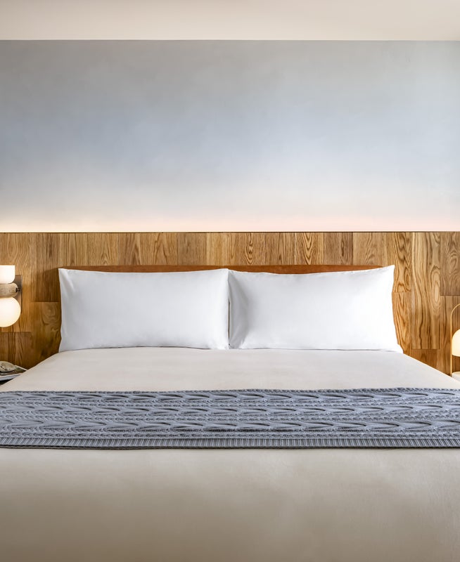 A king size bed with green potted plants on either side
