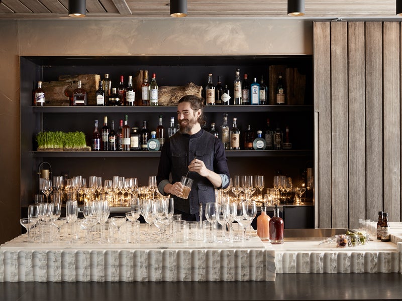 A bartender mixes a drink behind the Quarry Bar at 1 Hotel Brooklynn Bridge