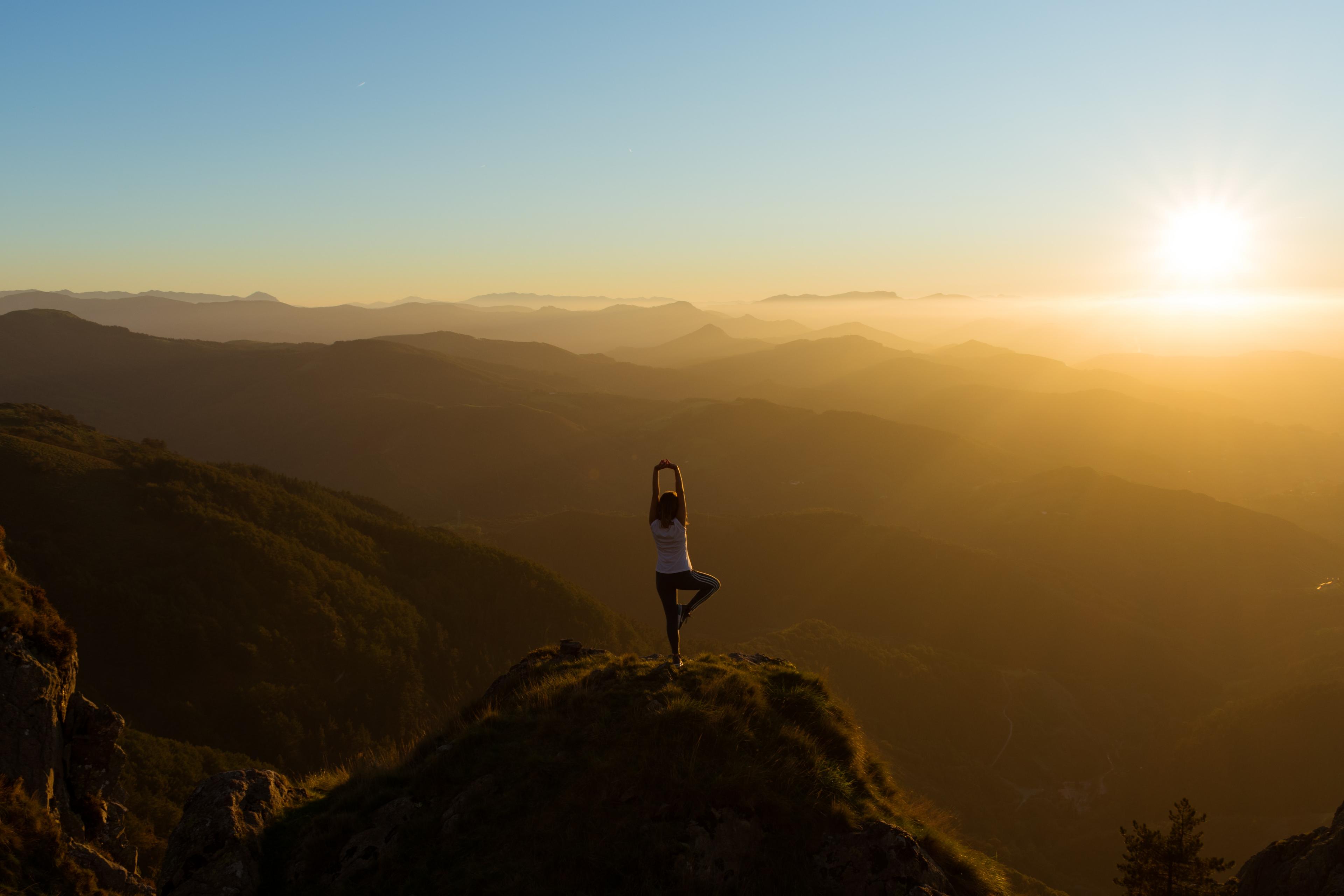 Person doing yoga atop a mountain
