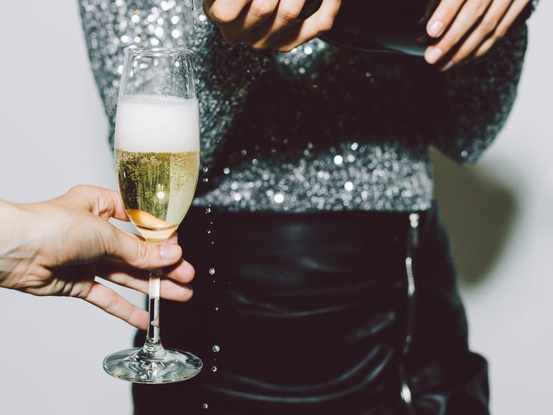 A person pouring a glass of champagne for another person