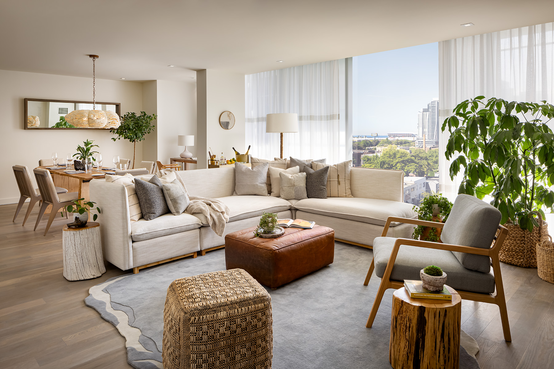 A living room area with a large white sectional sits in front of a large wooden dining room table.  