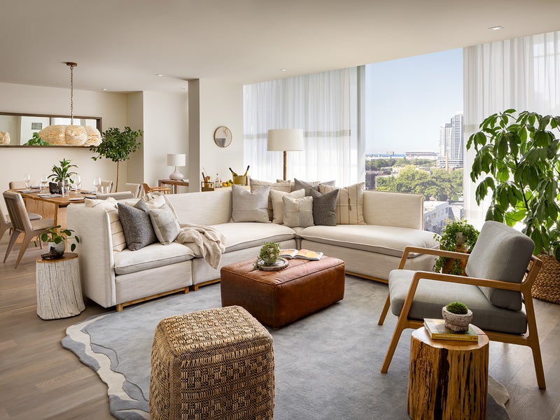 A living room area with a large white sectional sits in front of a large wooden dining room table.