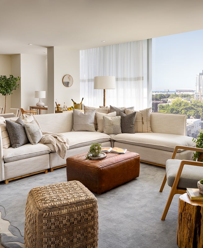 A living room area with a large white sectional sits in front of a large wooden dining room table.