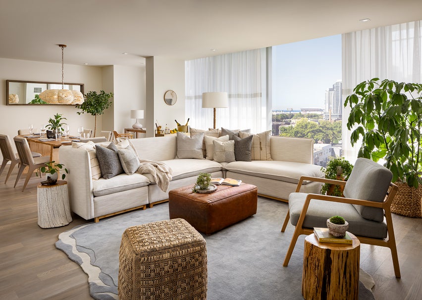 A living room area with a large white sectional sits in front of a large wooden dining room table.