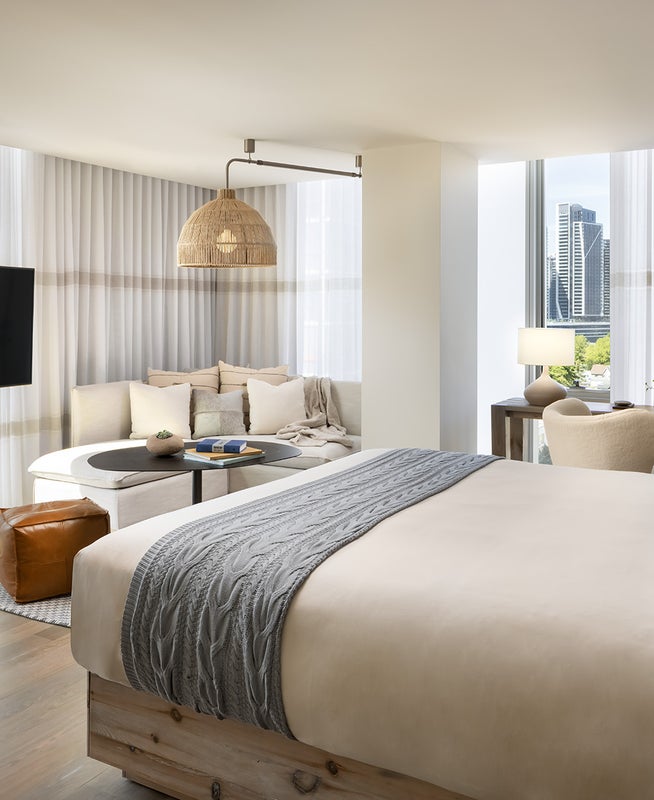 A king size bed centered in the middle of the room positioned in front of the television with views of the city beyond