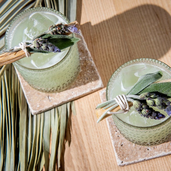 Two green colored cocktails with sage garnishes