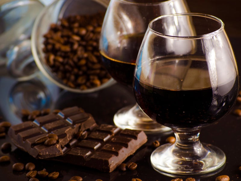 A glass of rum, a broken chocolate bar and cacao beans