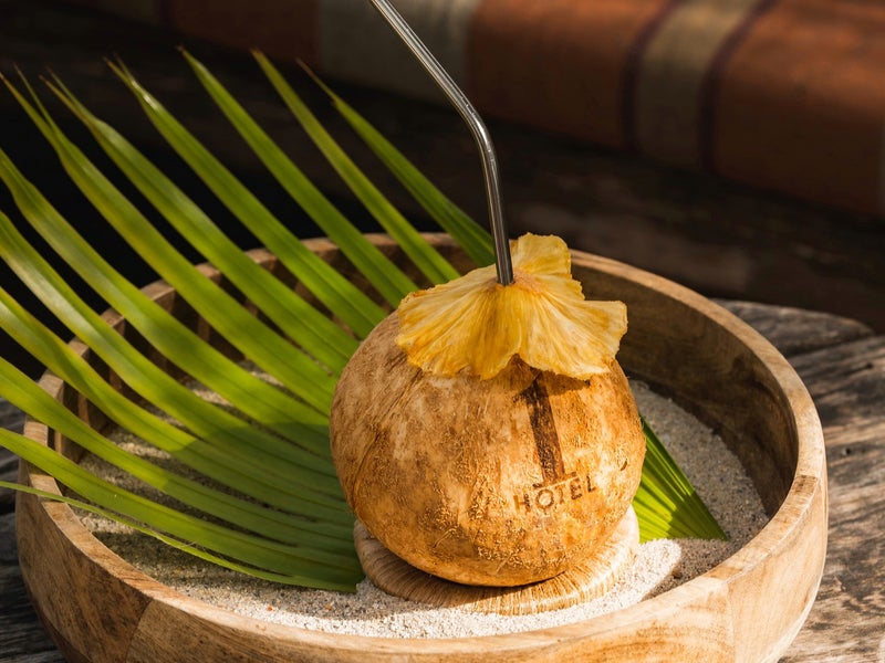 A coconut with the 1 Hotels logo and a straw