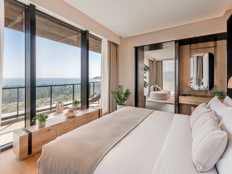 A bed facing the window which looks out to the ocean