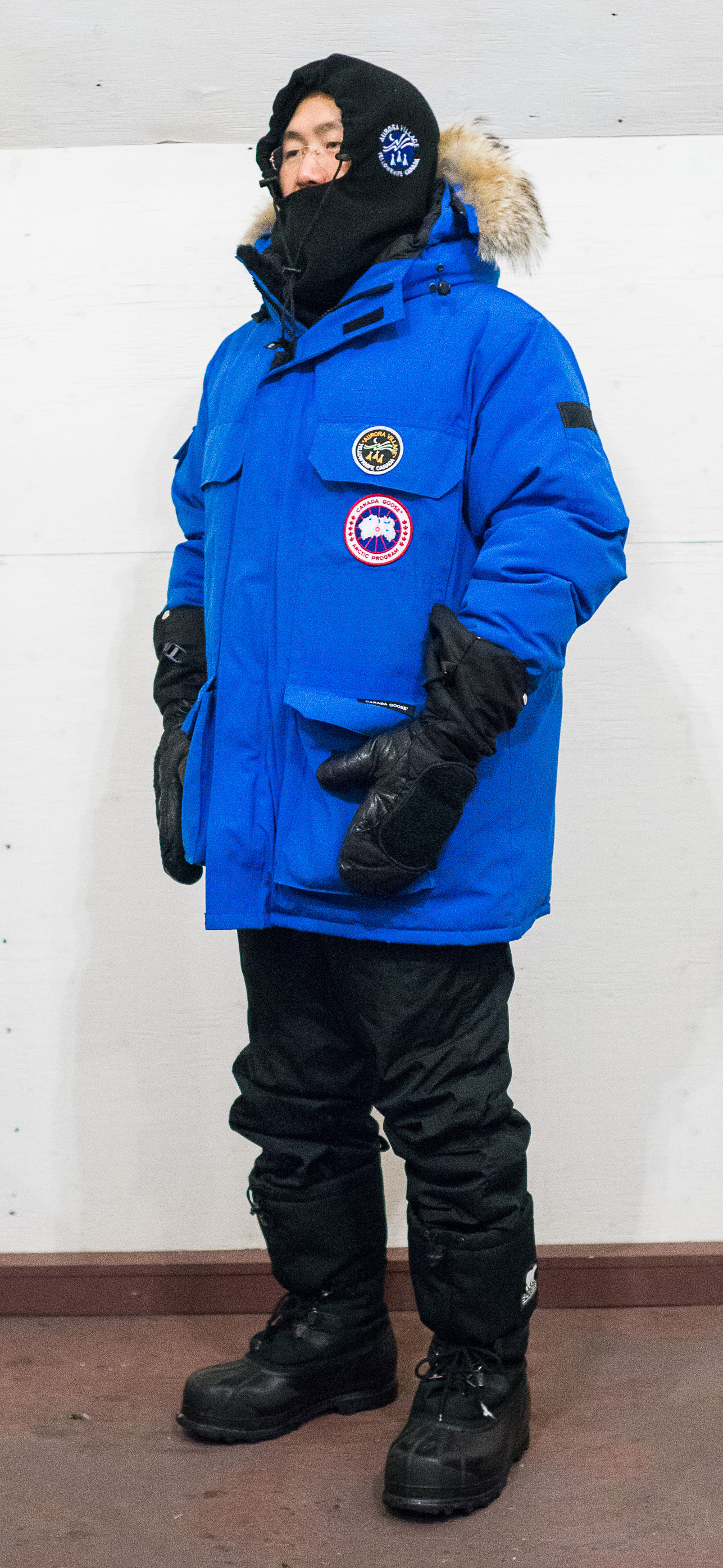 A person wearing a blue parka and black boots