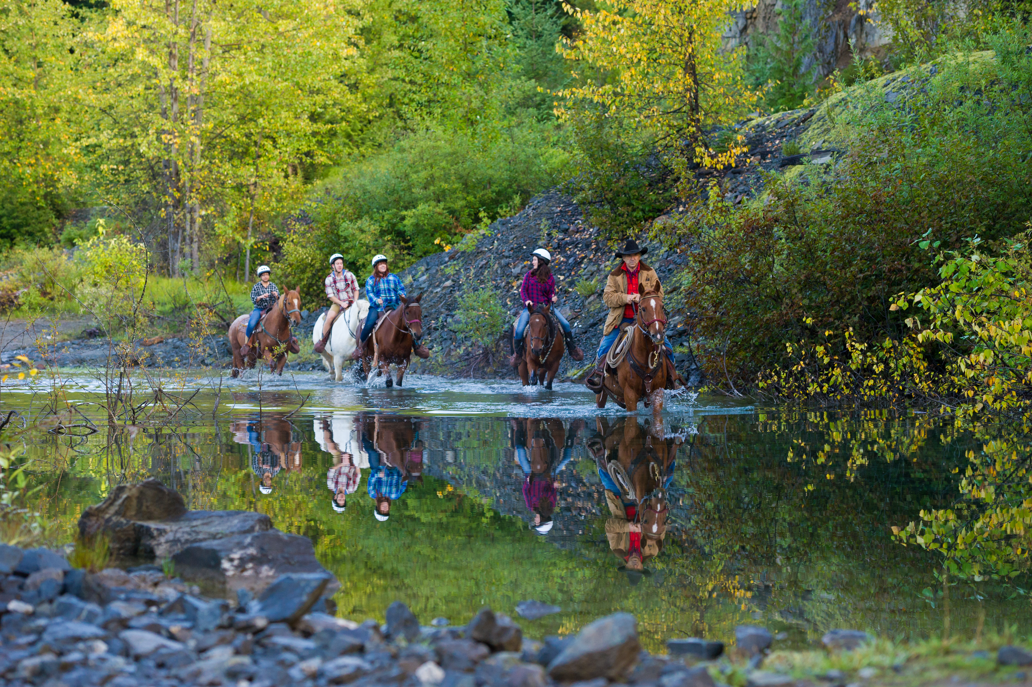 Group of people horseback riding through a river in Whistler