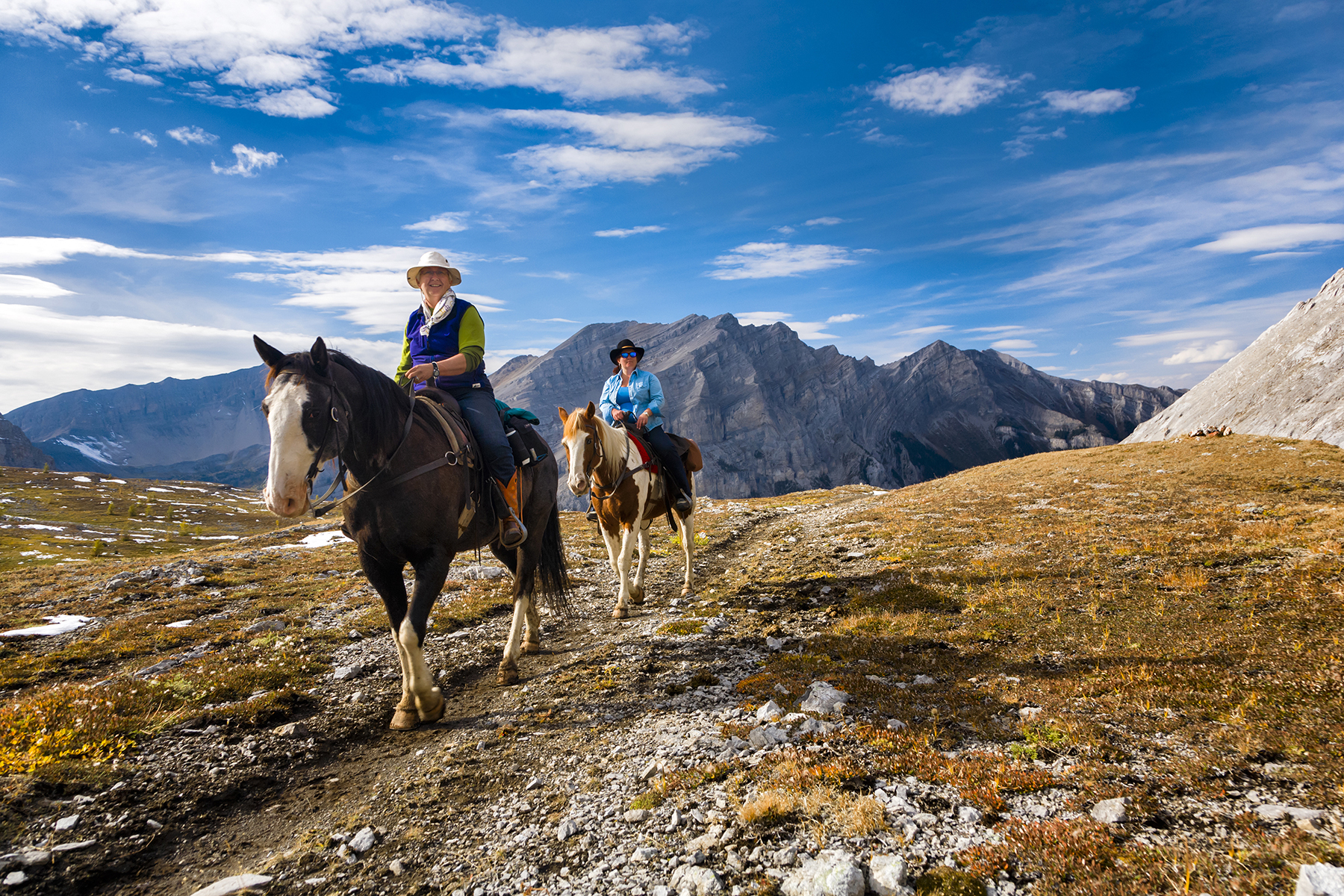 Couple horseback riding on a trail in the mountains in Banff National Park.