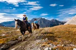 Couple horseback riding on a trail in the mountains in Banff National Park.